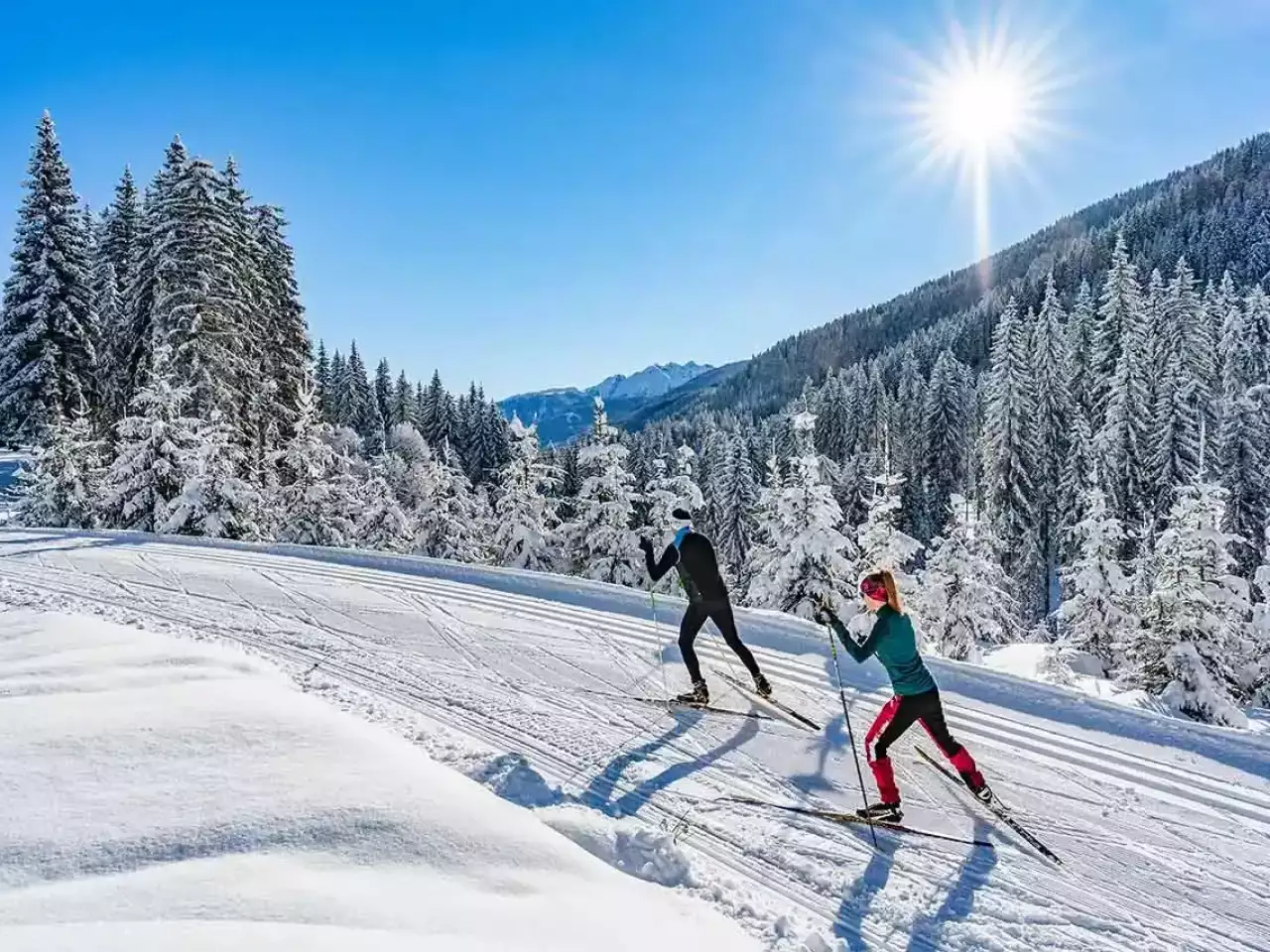 Langläufer mitten im verschneiten Wald bei Sonnenschein